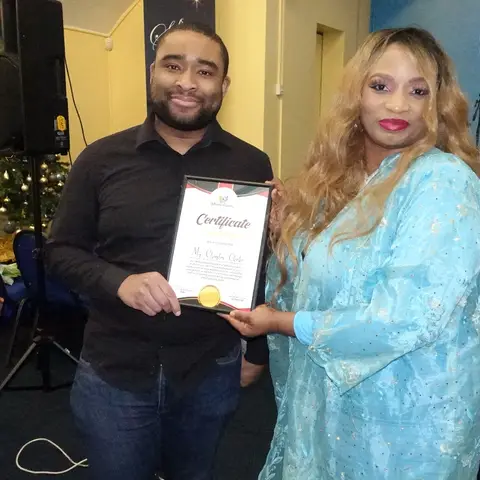 The presenter speaking into a microphone, addressing the audience with a 'Savior is Born' banner in the background.