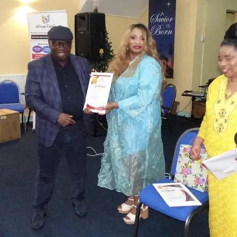 A man in a black shirt holding his certificate and posing for a photo with the presenter.