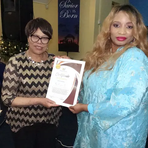 Three women in elegant outfits smiling together for a photo at a table set with green tablecloths and Christmas crackers.