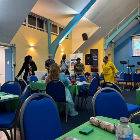 Guests mingling in the hall with a projector screen showing an image in the background.