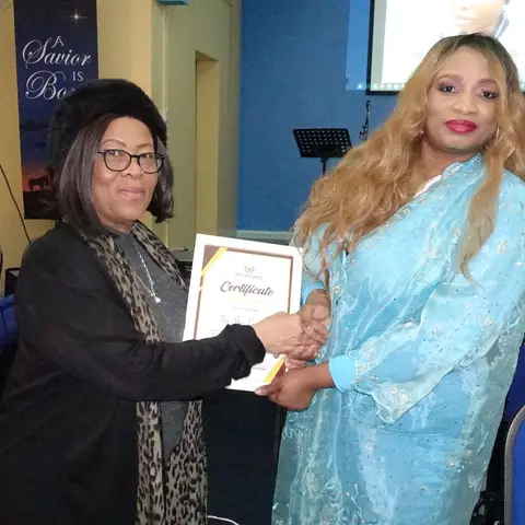 Two women shaking hands and smiling as one receives a certificate of appreciation during the ceremony.