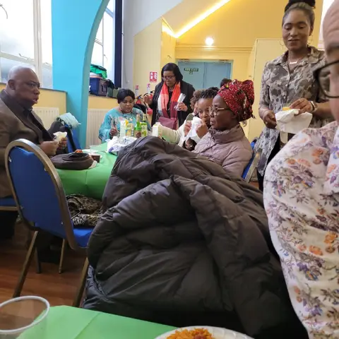 Guests seated at a table enjoying their meal, with a close-up of plates of food and drinks in the foreground.