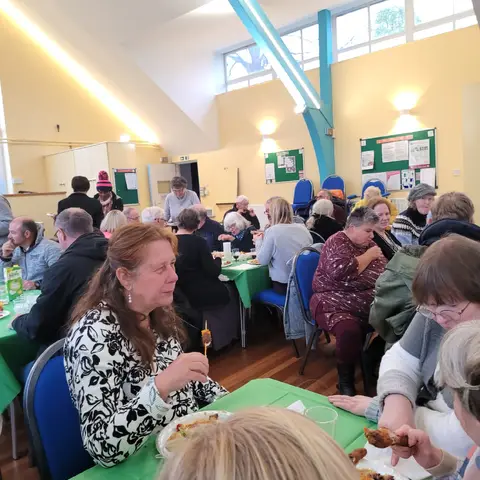 Guests eating and chatting at tables during the community outreach event.