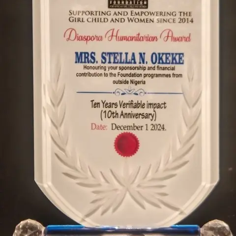 A glass shield award presented to Mrs. Stella N. Okeke by the Leadership Foundation for African Girl Child and Women for 'Diaspora Humanitarian' contributions, commemorating ten years of verifiable impact, dated December 1, 2024.