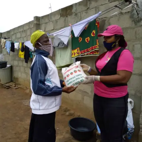 A group of women standing outdoors with a banner for African Girl Child and Women.