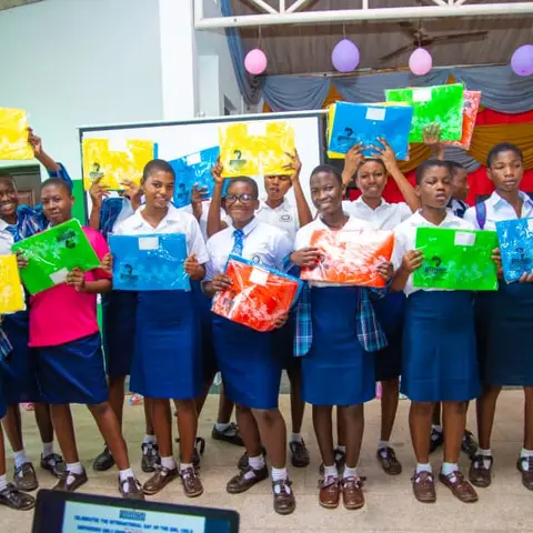 Schoolgirls in various uniforms proudly hold up colourful gift bags they received at the International Day of the Girl Child celebration.