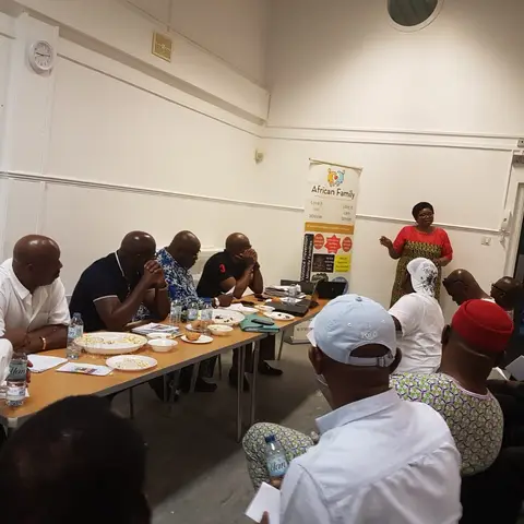 Two women in formal attire posing together in a wood-paneled hall.
