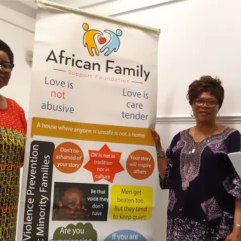 A group photo of people seated at a round table in a formal hall.