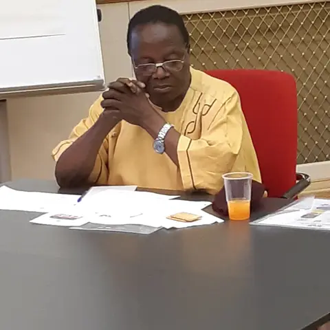 Guests seated at a formal event table in a wood-paneled hall.