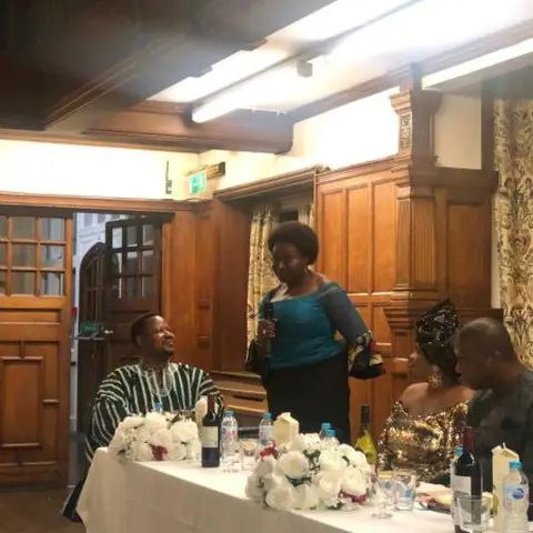 Two women standing in a conference room, one speaking into a microphone.