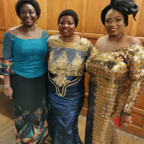 A large group photo of workshop participants standing in a conference room with red chairs.