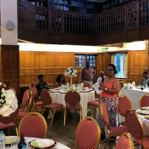 A presenter speaking to a seated audience at an educational seminar.