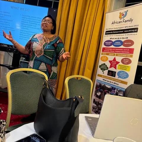 The presenter speaking next to a large African Family Support Foundation banner that highlights their NPO Award and community outreach programs.