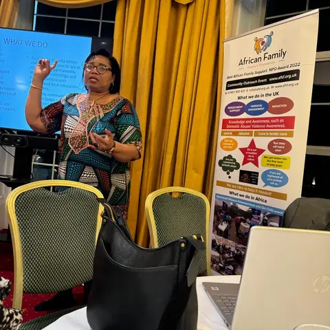 A close-up of the presenter gesturing during her talk, with the AFSF banner and a presentation screen visible in the background.