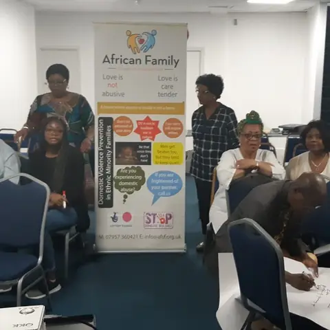 Participants gathered around a table and signing documents next to an African Family Support Foundation banner.