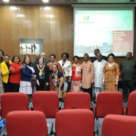 A group of staff and volunteers standing together in front of a Summer Gala Event banner.