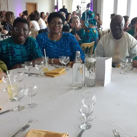 Five AFSF supporters and guests in African formal attire seated at a round dinner table, smiling for a photo.