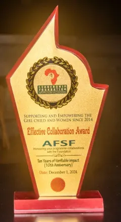 A gold and red shield-shaped award plaque from the 'Leadership Foundation for African Girl Child and Women'. It is titled 'Effective Collaboration Award' and presented to 'AFSF' for 'honouring your programme collaborations with the Foundation'. It also commemorates 'Ten Years of Verifiable impact (10th Anniversary)' and is dated 'December 1, 2024'.